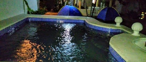 A swimming pool with a tiled edge, a small waterfall feature, and a decorative fountain.