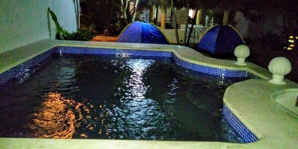 A swimming pool with a tiled edge, a small waterfall feature, and a decorative fountain.