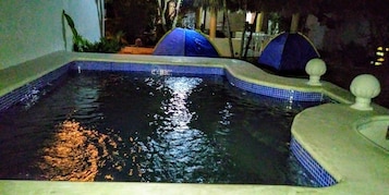 Una piscina con borde de azulejos, una cascada pequeña y una fuente decorativa.