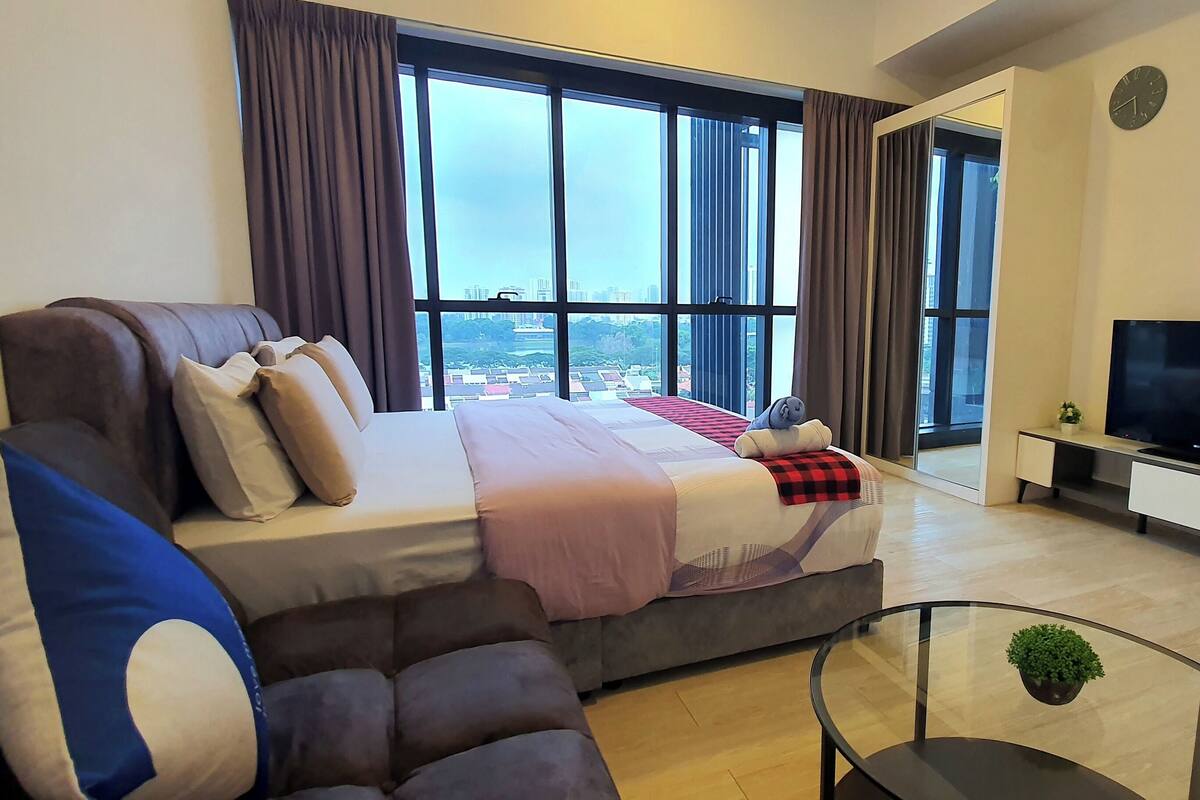Une chambre d’hôtel moderne dotée d’un grand lit, d’un canapé, d’une télévision et d’un balcon offrant une vue sur la ville.