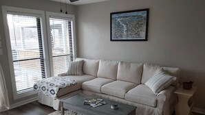 A living room with a beige sofa, a coffee table, a patterned rug, and a framed map on the wall.