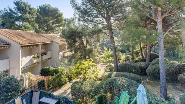 A residential area with a house featuring a tiled roof, a balcony, and a garden with various plants and trees. - Duplex Cigarra - Welkeys (Bandol)