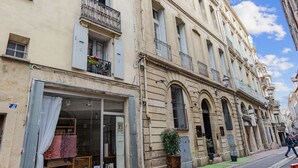 A historic building with multiple balconies, large windows, and a storefront with curtains.