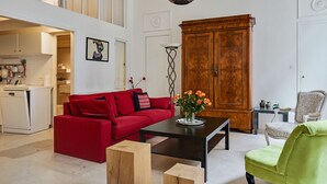 A modern living room with a red sofa, a green armchair, a wooden coffee table, and a large wooden cabinet.