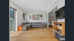 Una sala de estar moderna con un sofá modular, un televisor de pantalla plana y obras de arte en las paredes.