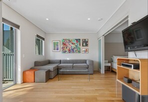 Ein modernes Wohnzimmer mit einer Eckcouch, einem Flachbildfernseher und Kunstwerken an den Wänden.