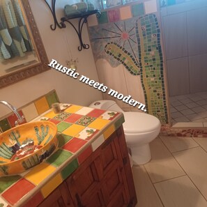 Un baño con un lavabo rústico y una ducha moderna.
