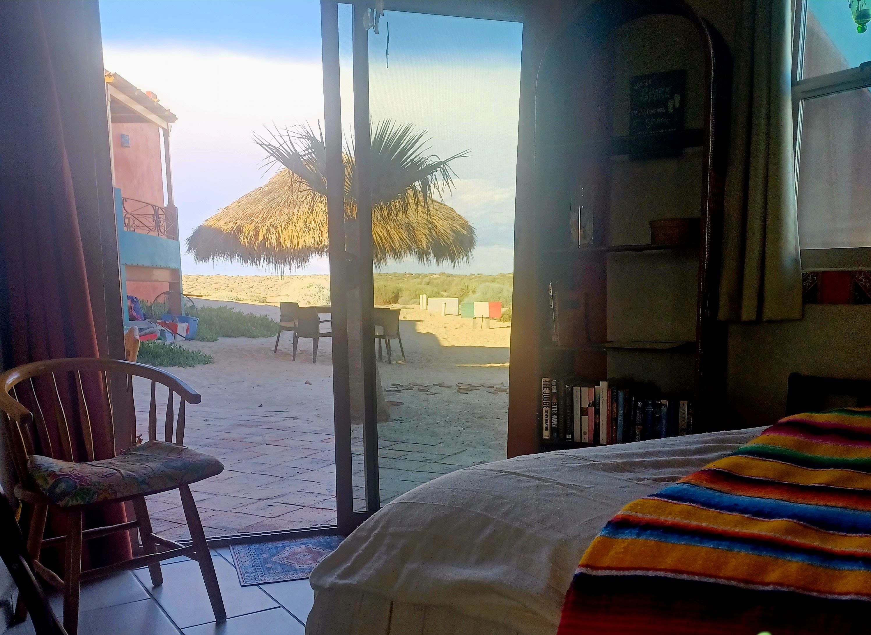 A room with a bed, a chair, and a view of a desert landscape.
