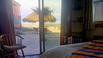 A room with a bed, a chair, and a view of a desert landscape.