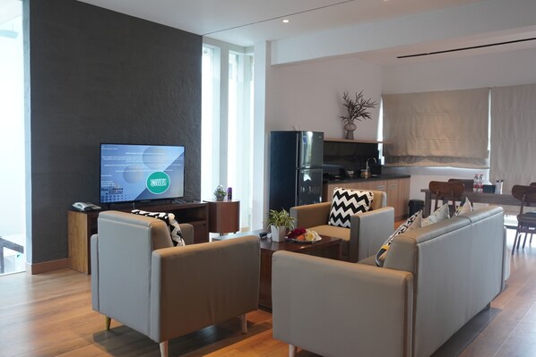 Una sala de estar moderna con televisor de pantalla plana, asientos cómodos, una zona de cocina y un comedor.