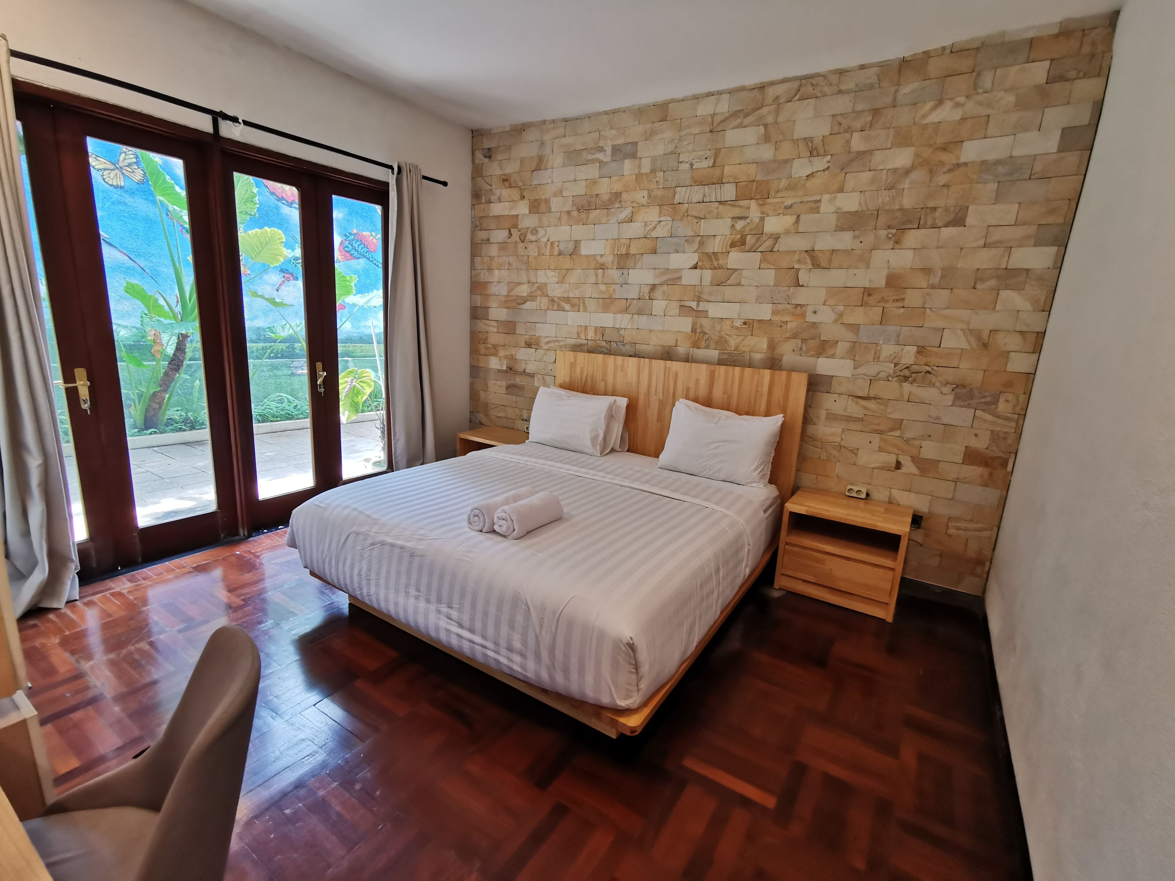 Un dormitorio con cabecera de madera, una cama grande con ropa blanca, una mesita de noche de madera y una silla.