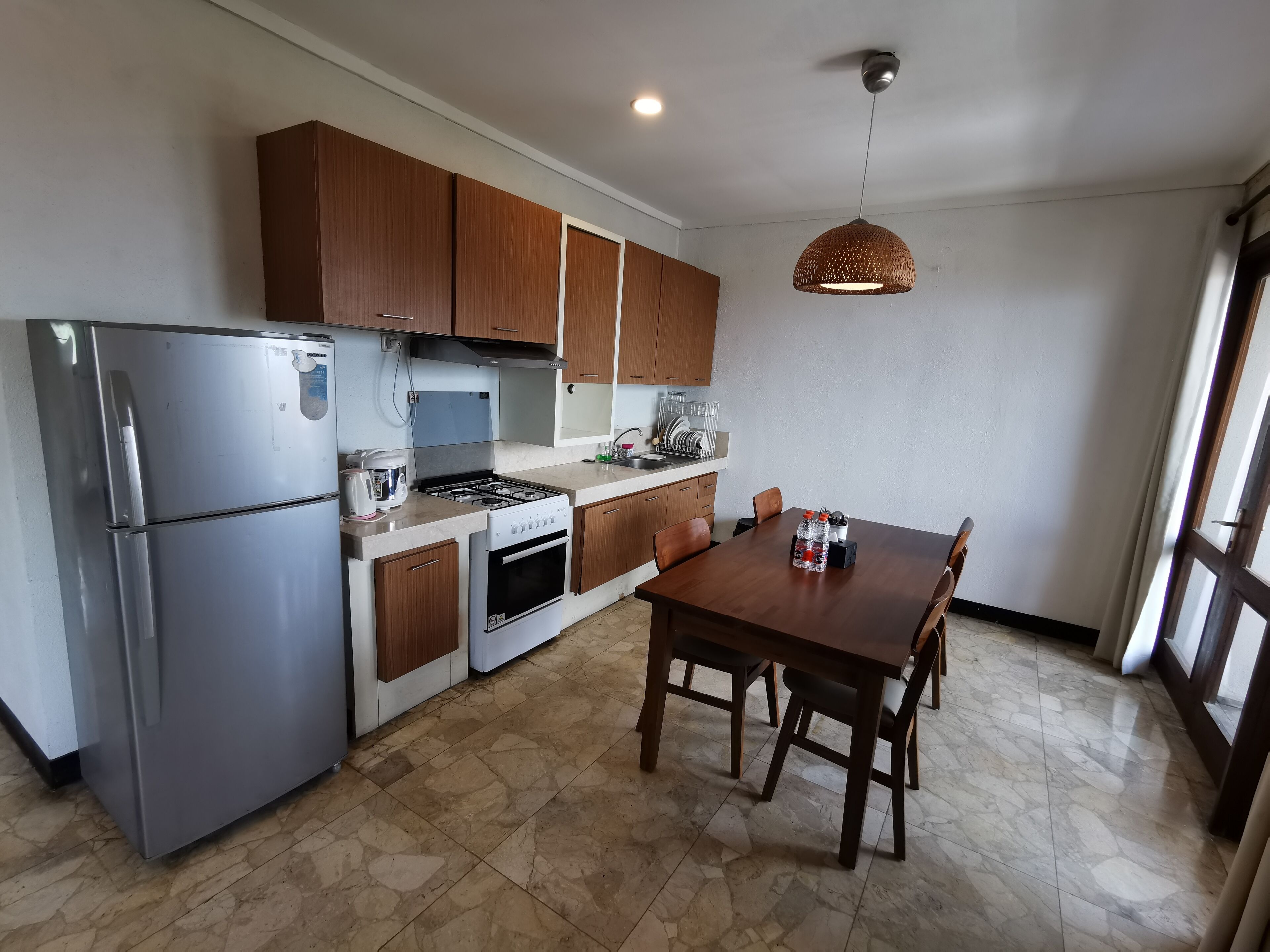 Una cocina moderna con electrodomésticos de acero inoxidable, armarios de madera y una zona de comedor con mesa y sillas.