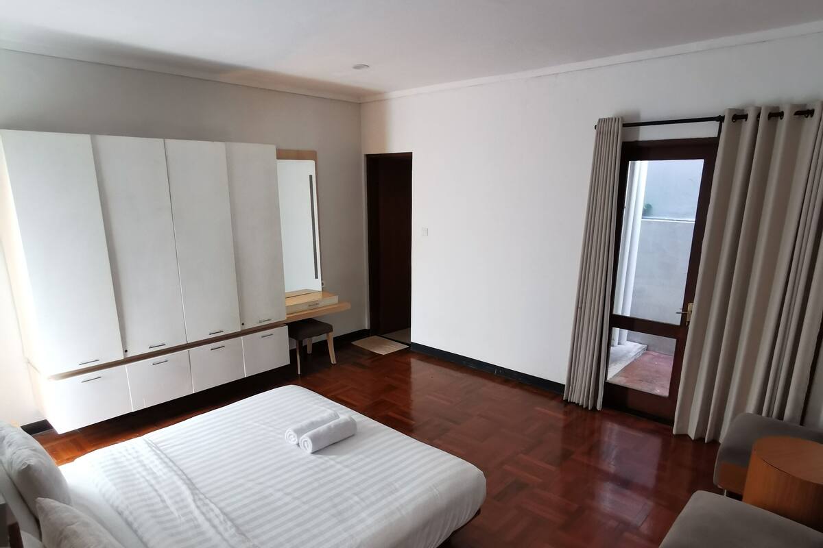 Une chambre d’hôtel avec un grand lit, un bureau, une chaise et une fenêtre avec des rideaux.