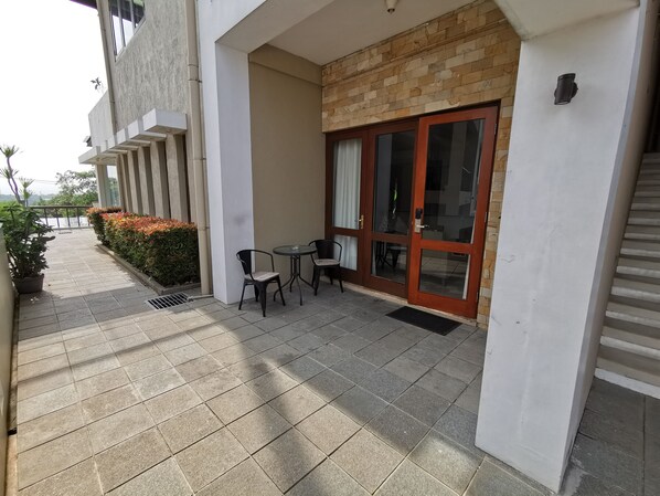 Un espace extérieur abrité, doté d’une table et de chaises, d’une porte-fenêtre coulissante et de plantes en pot.