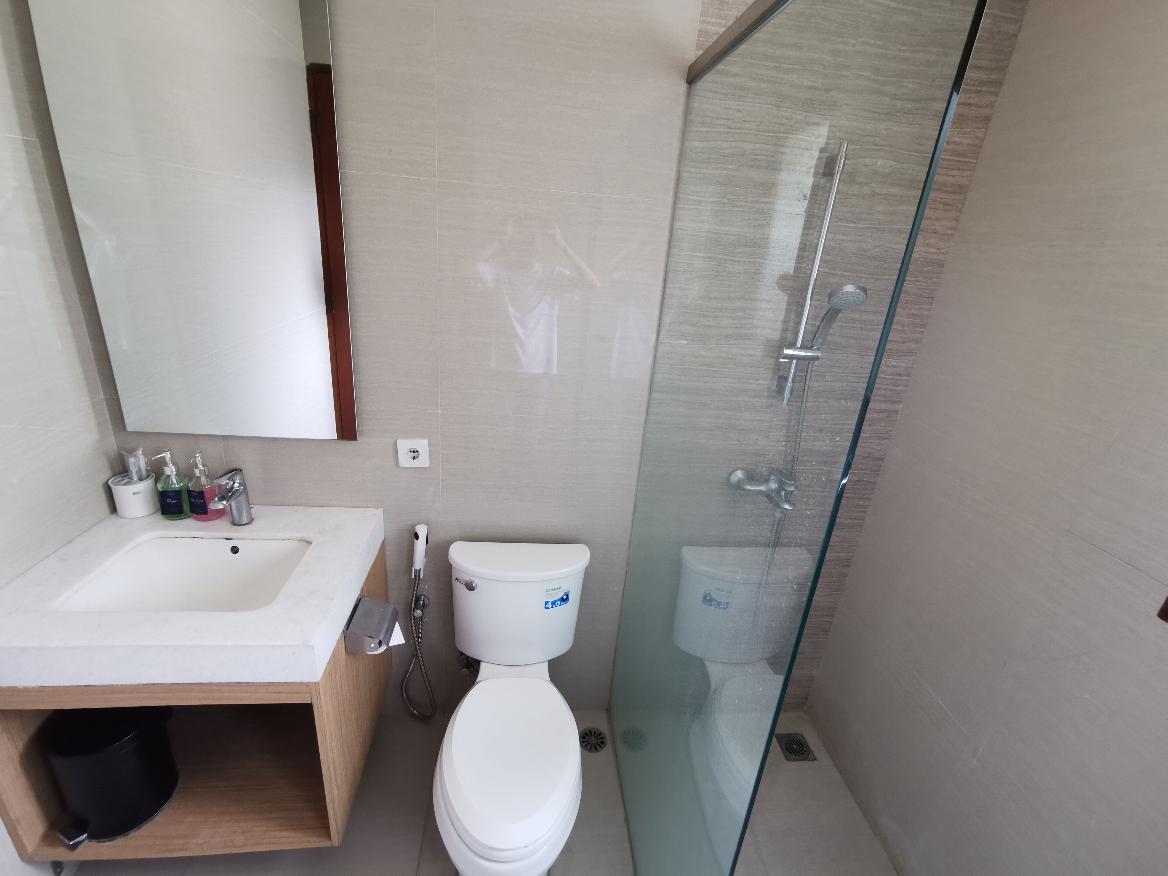A modern bathroom with a glass-enclosed shower, a white sink, and a toilet.