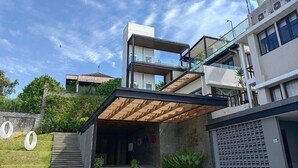 A modern multi-story building with a covered entrance, outdoor seating area, and a staircase leading to the entrance.