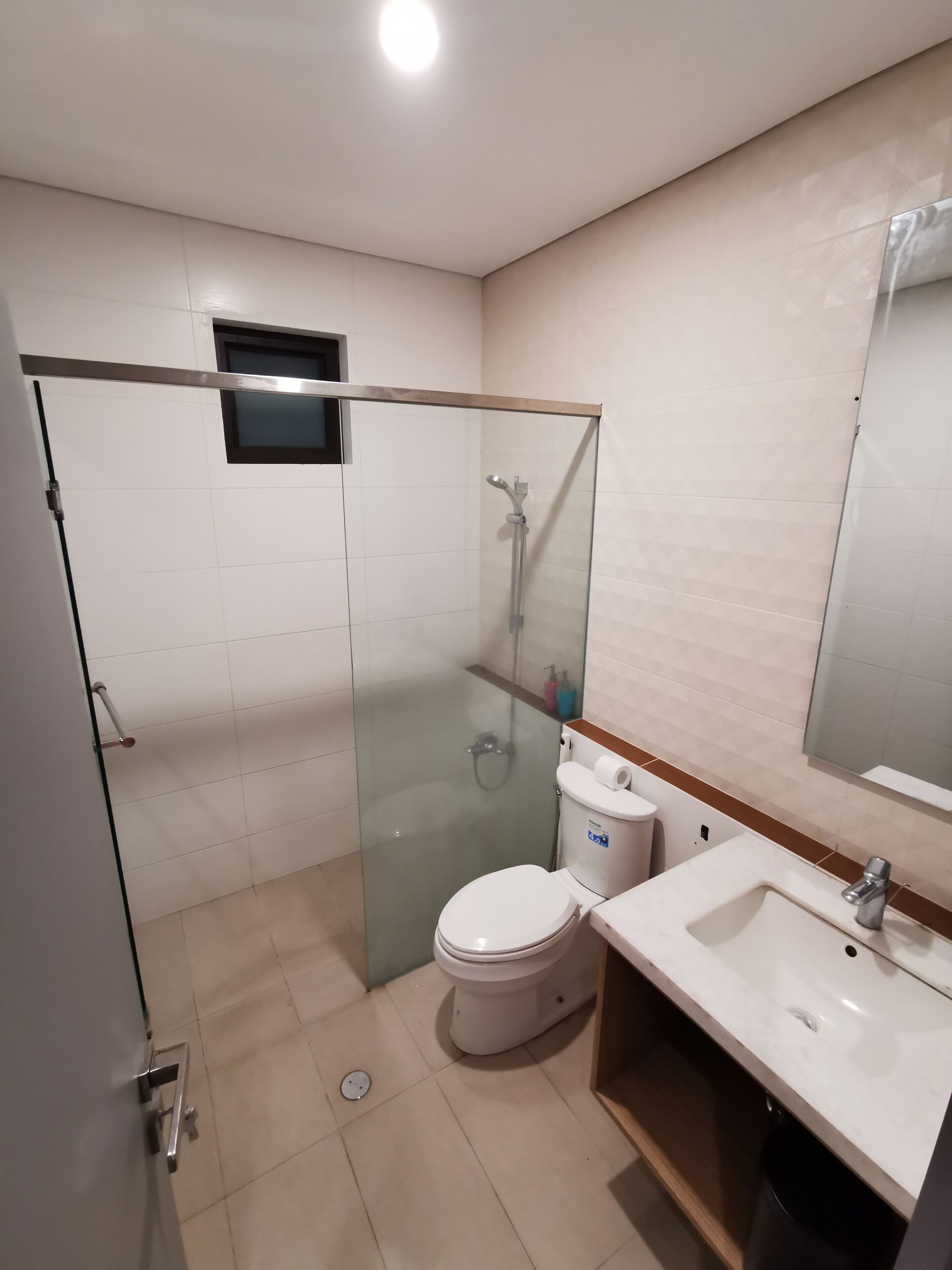 A modern bathroom with a glass-enclosed shower, a toilet, and a sink.