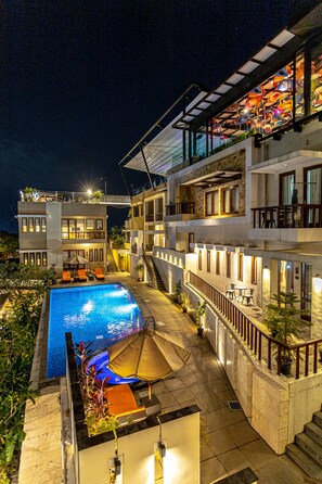 Un immeuble moderne à plusieurs étages, doté d’une piscine, d’un espace extérieur aménagé et d’un balcon offrant une vue panoramique.