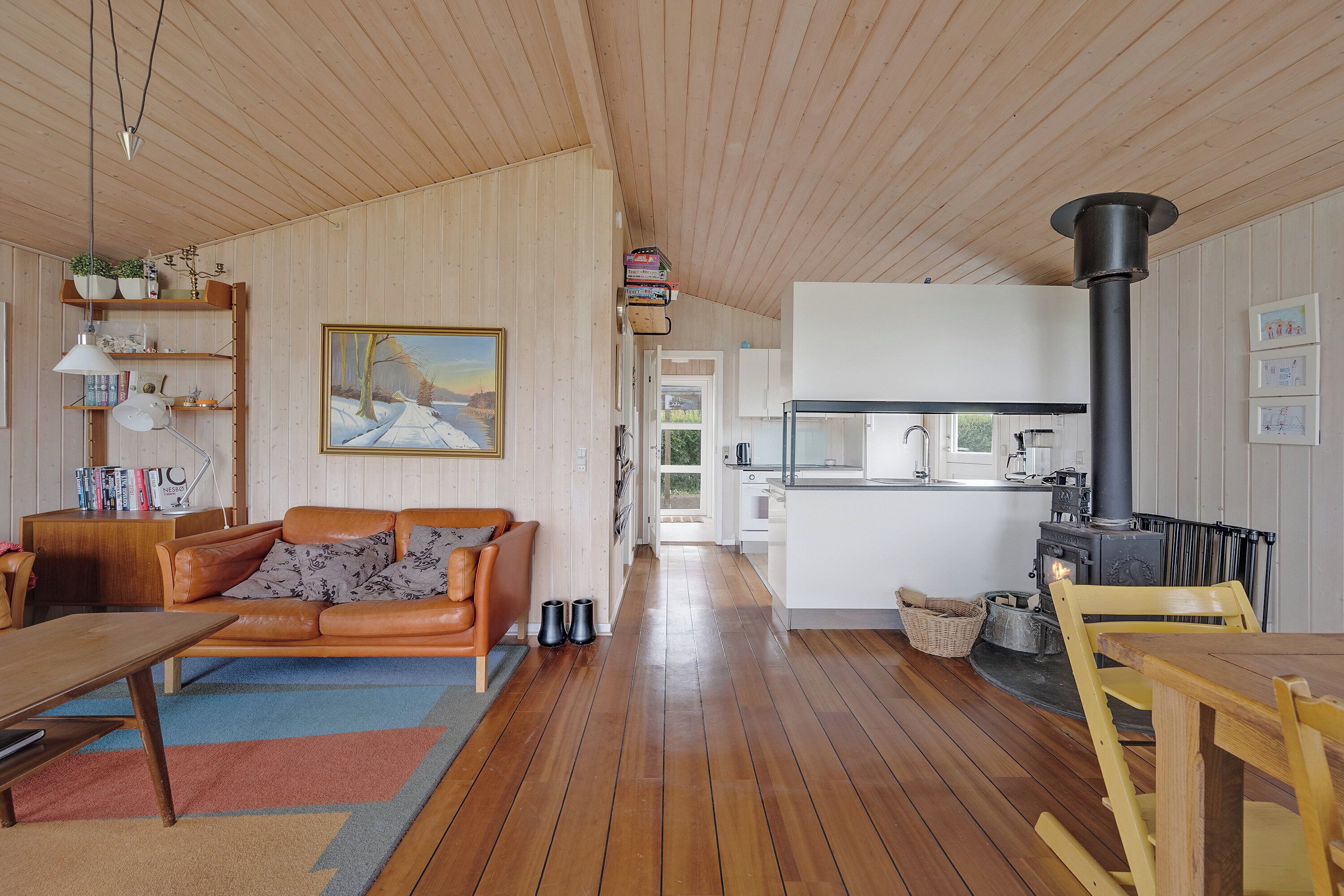 Una sala acogedora con sofá, mesa de comedor, chimenea y cocina al fondo.