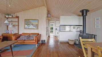 Una sala acogedora con sofá, mesa de comedor, chimenea y cocina al fondo.