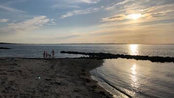 Une plage au coucher du soleil, avec une côte rocheuse et des empreintes de pas.