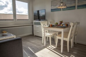 Ein Essbereich mit Tisch, Stühlen, einem Fernseher und einer Heizung.