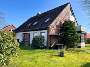 A house with a sloped roof, a brick exterior, and a small porch. - DA25/1 - Family-friendly, comfortable vacation apartment with garden use - House (Cuxhaven)