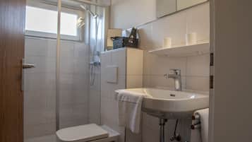 Ein Badezimmer mit Dusche, Toilette, Waschbecken und Handtuchhalter.