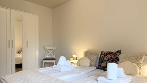 Una camera da letto con un letto grande, un armadio, una sedia e un comodino con una lampada.