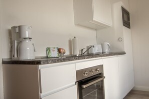 Une cuisine moderne équipée d’un four encastré, d’une machine à café et d’un four à micro-ondes.