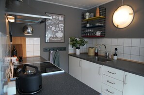 A modern kitchen with a stove, kettle, sink, and various kitchen utensils.