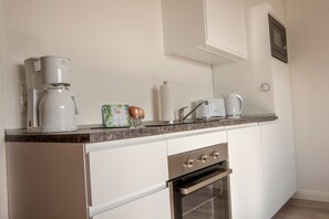 Una cocina equipada con cafetera, tostadora, microondas y un armario.