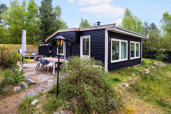 A cabin with a patio, a table, and chairs. - Cozy family home near beach and forest (Højby)