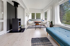 Une piĂšce chaleureuse avec une cheminĂ©e, un canapĂ©, une table Ă manger et de grandes fenĂȘtres.