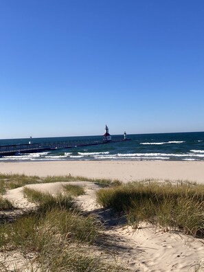 Ein Strand mit einem Leuchtturm und einer Mole, die sich ins Meer erstreckt.