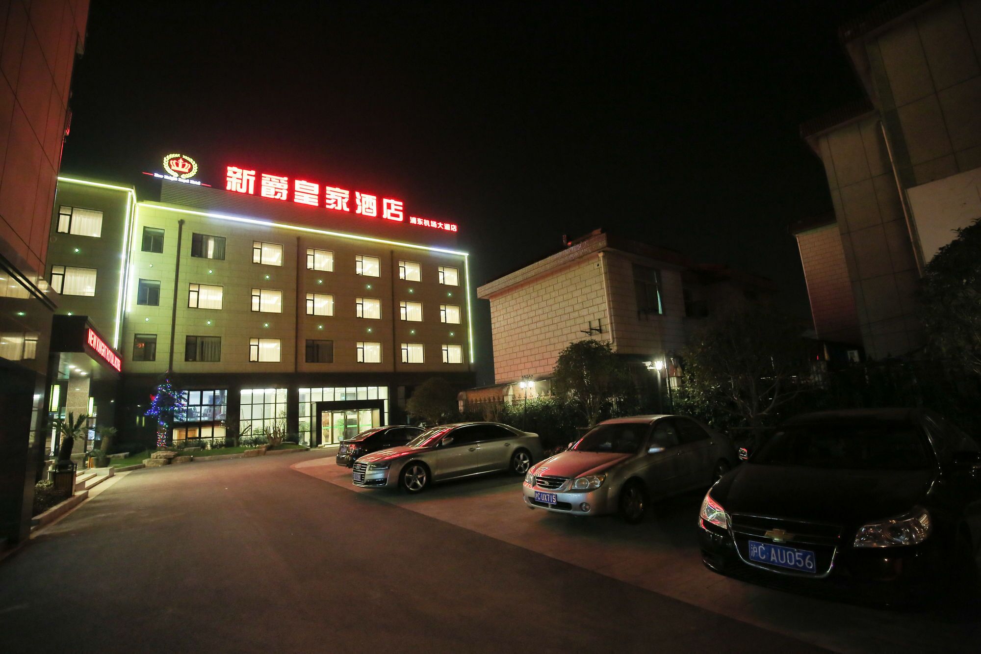 A hotel with a prominent sign, multiple floors, and parked cars in front.