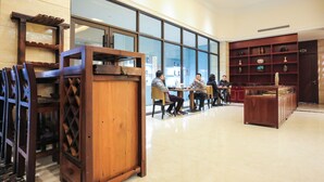 Un vestíbulo espacioso con un mostrador de recepción de madera, una zona de estar con mesas y una amplia exhibición de objetos decorativos.