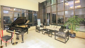 Un vestíbulo con un piano de cola, sofás, una mesa de centro y una planta en maceta.