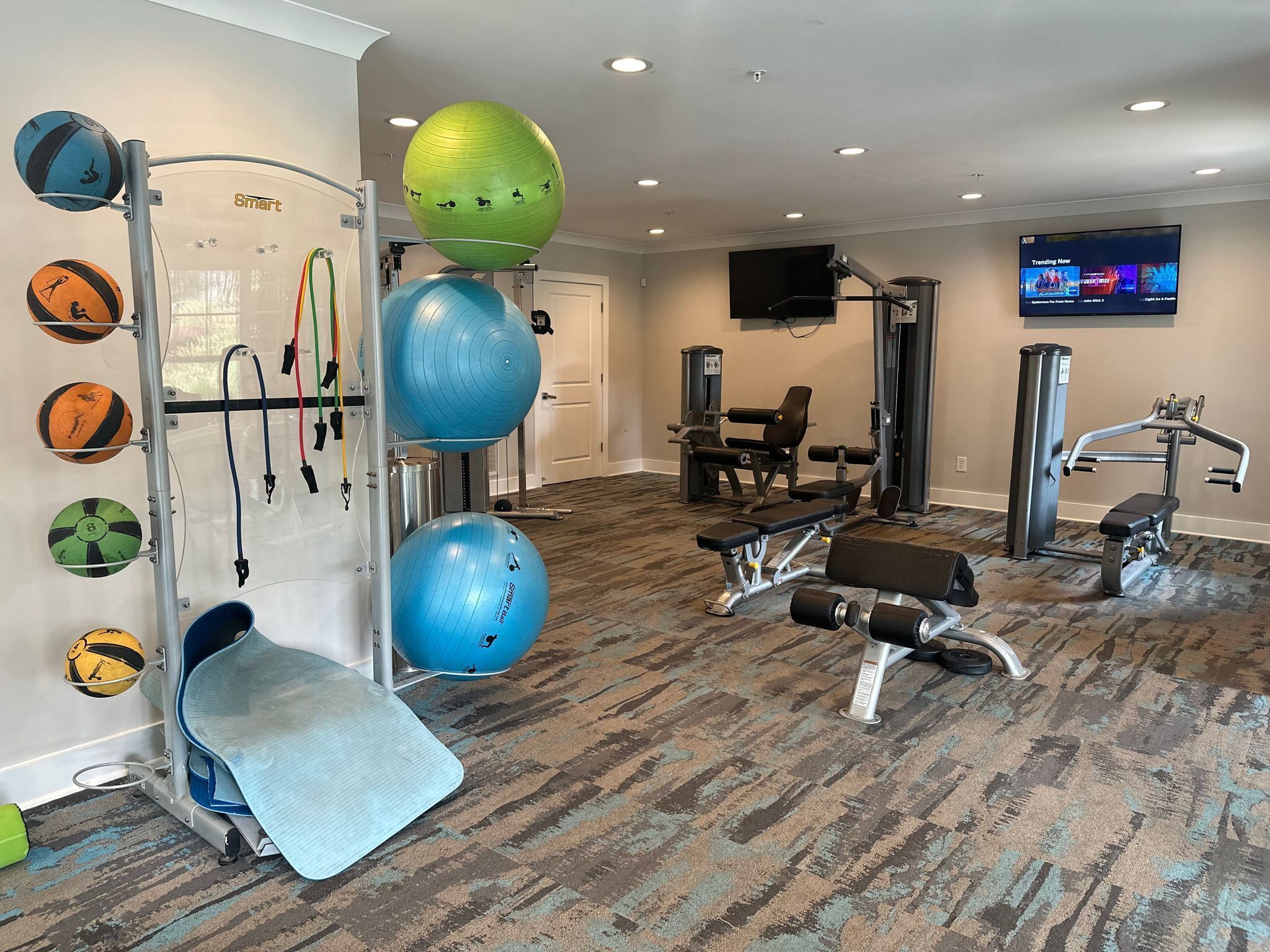 Una palestra con attrezzature per esercizi, una televisione e un tappeto decorato.