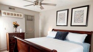 A bedroom with a wooden bed, white bedding, a ceiling fan, a dresser, a vase with flowers, and two framed artworks on the wall. - A peaceful Lake view by The Battery (Smyrna)