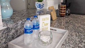 A kitchen counter with a tray holding water bottles, a glass, and a card with the text "FAITH Over FEAR". - A peaceful Lake view by The Battery (Smyrna)