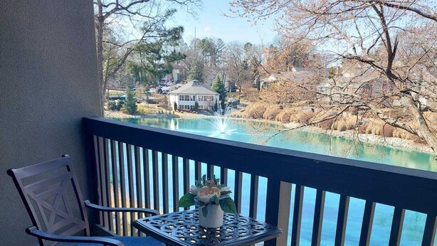 A balcony with two chairs and a small table, overlooking a body of water and a residential area. - A peaceful Lake view by The Battery (Smyrna)