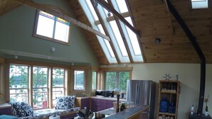 A spacious kitchen with a large island, wooden beams, and skylights. - Beachfront Guest Cottage in Antigonish (Antigonish)