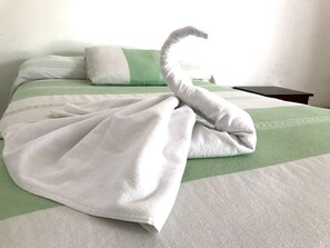 Una cama bien hecha, con una toalla dispuesta en un nudo decorativo.