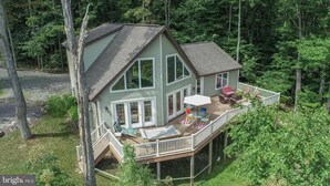 Ein zweigeschossiges Haus mit Terrasse, großen Fenstern und einer überdachten Veranda.