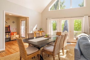 A dining area with a large table, wicker chairs, and a view of the outdoors through a sliding door. - Spacious family-friendly chalet w/fenced dog run & large deck near the lake/Wisp (Oakland)