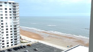 Ein Hochhaus-Hotel mit Parkplatz und Blick auf den Strand.