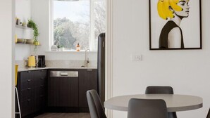 A modern kitchen with dark cabinetry, a round dining table with four chairs, and a pendant light.
