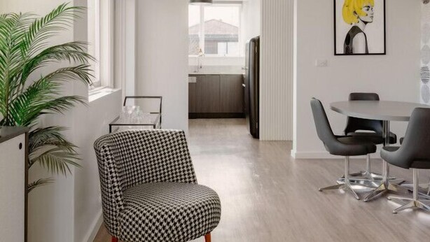 A modern living room with a houndstooth armchair, a dining table with chairs, and a large window.