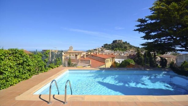 A swimming pool with a view of a town and a hill in the background. - Rental apartment with community pool in Begur (Begur)